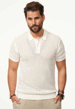 Weißes gestricktes Poloshirt mit einem Netzmuster, geripptem Kragen, kurzen Ärmeln und geradem Saum. Akzentuiert mit zwei Knöpfen am Hals.