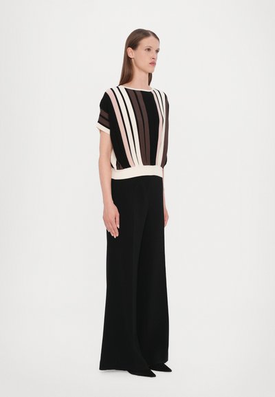 Black wide-leg pants paired with a striped short-sleeve top in cream, pink, and brown, featuring a gathered waist and soft texture.