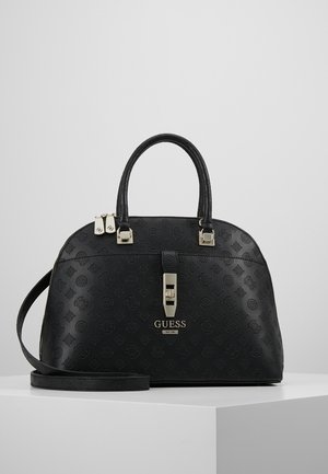 Sac à main noir Guess avec motif embossé, doubles poignées, bandoulière réglable, fermeture à serrure frontale et plaque logo en métal sur une surface blanche.