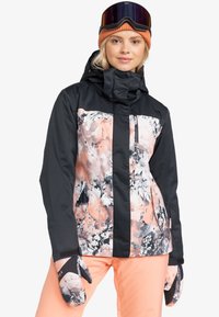Ski jacket with black and floral peach pattern, featuring a zip pocket, high collar, and adjustable cuffs. Pair of matching mittens on hands.