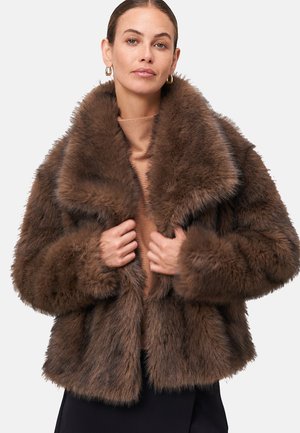 Bruine faux fur jas met een brede kraag, cropped ontwerp en lange mouwen. Zachte textuur, weelderige uitstraling en snug fit rond het lichaam.