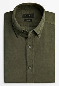 Chemise en velours côtelé olive pliée, avec un col à boutons et une étiquette de marque visible dans la zone du cou.