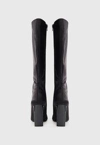 Cizme negre până la genunchi din material neted, cu un design care se mulează pe picior. Au un toc gros și înalt și închidere cu fermoar la spate.