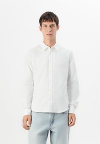 Witte overhemd met lange mouwen, gemaakt van een gladde stof, met een klassieke kraag en rechte snit, gedragen met lichtblauwe spijkerbroek.
