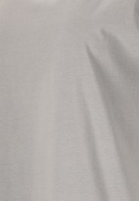 Ljusgrå bomullstyg, slät textur, med lätt drapering och subtil lyster, som visar på enkelhet i design och färg.