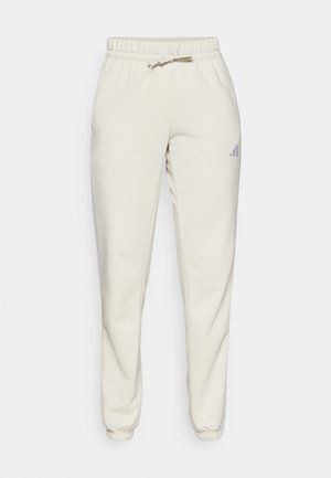 Ljust beige joggerbyxor i mjukt tyg, med resårmidja och dragsko samt ribbade mudd. Inkluderar en liten blå logotyp på sidan.