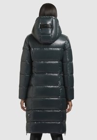 Garšs pūkains mētelis tumši zaļā krāsā, izgatavots no spīdīga ūdensizturīga materiāla. Ar kapuci, quiltota dizaina un sānu kabatām. Melns logo akcentus tuvumā apakšmalai.