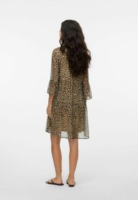 Abito a stampa leopardata con maniche a tre quarti, tessuto trasparente, design a strati e vestibilità comoda. Indossato con sandali piatti.