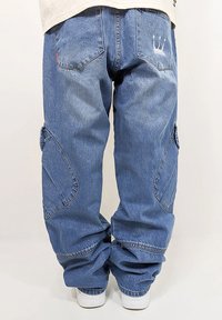Blue denim cargo pants with a loose fit, featuring side pockets, a cropped length, and embroidered crown detail on the back pocket.
