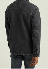 Giacca di jeans nera con colletto puntato, polsini con bottoni e dettagli sulla fascia posteriore. Presenta una vestibilità dritta e una texture di peso medio.