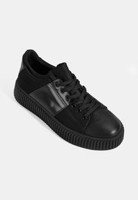 Schwarze Sneakers mit einer Kombination aus strukturiertem Leder und glattem Material, runder Zehenpartie und einer gerippten Gummisohle mit Schnürdesign.