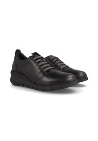 Zapatillas negras de cuero con cordones elásticos y punta redonda. Presentan un acabado texturizado y un ligero tacón en cuña para mayor soporte.