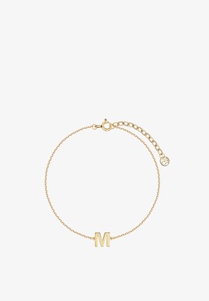 Złota bransoletka łańcuszkowa z wyraźnym charms z literą "M", z karabińczykiem i regulowaną długością. Gładka tekstura o błyszczącym wykończeniu.