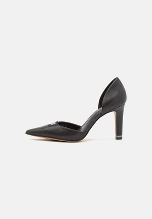 Chaussure à talon haut en cuir noir à bout pointu, avec une découpe d'Orsay et un talon fin de hauteur moyenne sur un fond blanc uni.