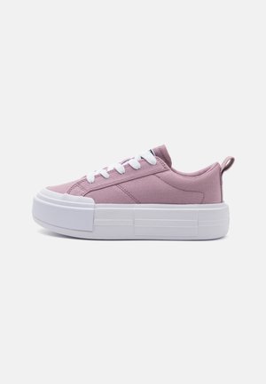 Sapatilha de lona rosa com sola de borracha branca, bico redondo e atacadores planos. Apresenta uma aba traseira para facilitar o calçar e um design minimalista.