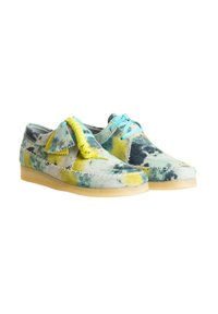Flerfarvede ruskindsko med et tie-dye mønster i blå, gul og grøn, med en let beige gummisål og dekorative snørebånd.