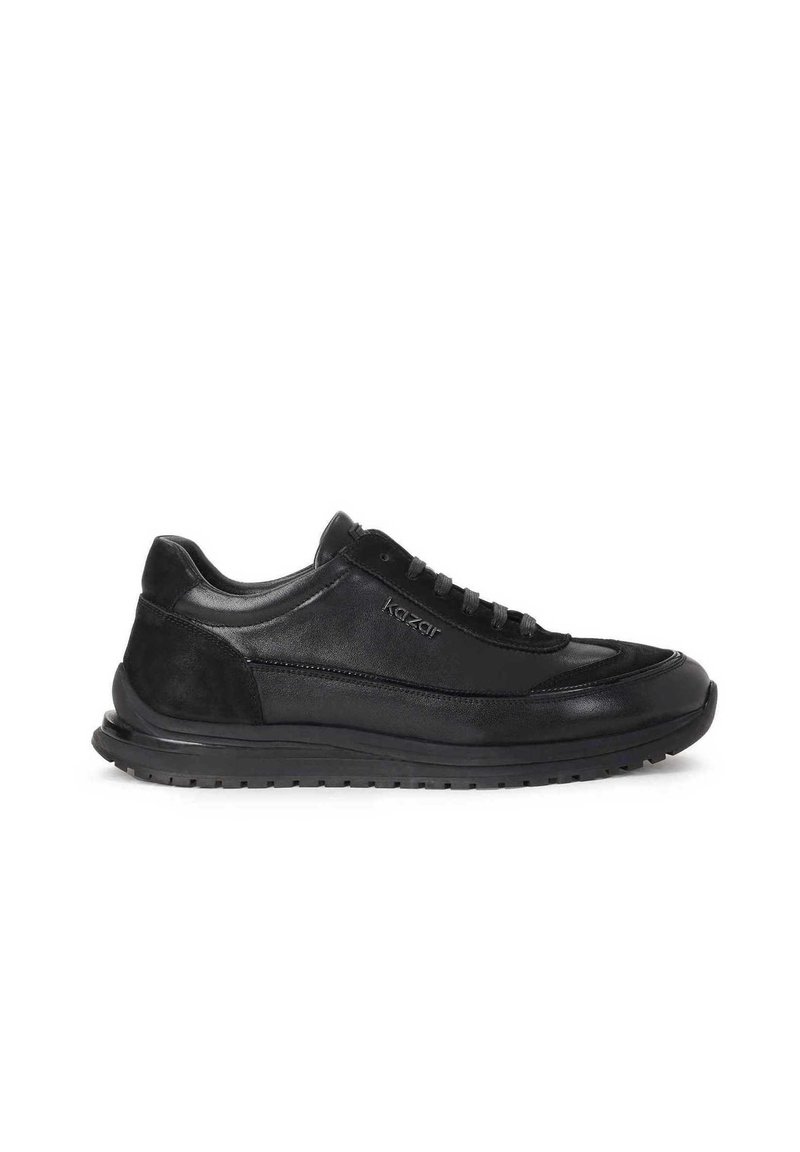Zapatilla negra con una mezcla de cuero liso y ante, puntera redondeada, cuello acolchado y suela de goma texturizada. Presenta cordones y logotipo.