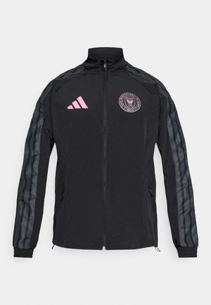 Veste de sport noire avec logo rose, fermeture éclair à l'avant, col montant, et manches légèrement texturées à rayures noires et grises.