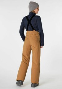 Pantaloni da sci marroni impermeabili con bretelle nere regolabili, tasche laterali e taglio dritto, indossati sopra un top a maniche lunghe blu navy.