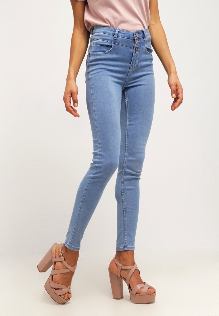 Jean skinny taille haute bleu clair en denim avec une texture lisse. Comprend une fermeture à trois boutons et deux poches avant.