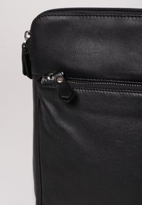 Black leather bag with a smooth texture, featuring a zippered pocket and silver hardware. Compact design with minimal visible stitching details.