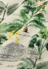 Tissu avec des palmiers verts détaillés, des plantes tropicales, des fleurs jaunes et des croquis architecturaux noirs sur un fond beige clair.