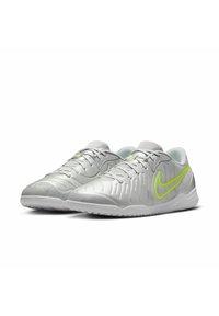 Silver athletic shoes with a textured upper, mesh materials, green accents, and a patterned sole. Laced design with a padded collar.