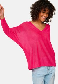 Rosa, locker sitzender V-Ausschnitt-Pullover mit langen Ärmeln. Hergestellt aus einem leichten, durchsichtigen Stoff, mit einer entspannten Silhouette und weichem Material.