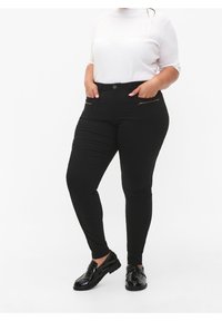 Czarne dopasowane dżinsy z zamkami błyskawicznymi i gładką teksturą, w połączeniu z białą koszulą z krótkim rękawem i błyszczącymi czarnymi loafersami.