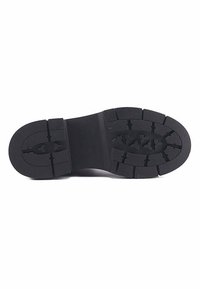 Melnas gumijas kurpes zole ar raupju protektoru, biezu papēdi un iegrieztu zīmola logotipu centrā.