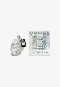 Schedelvormige parfumfles in metallic zilver met een zwart etiket; inclusief een holografische doos met QR-code en productdetails.