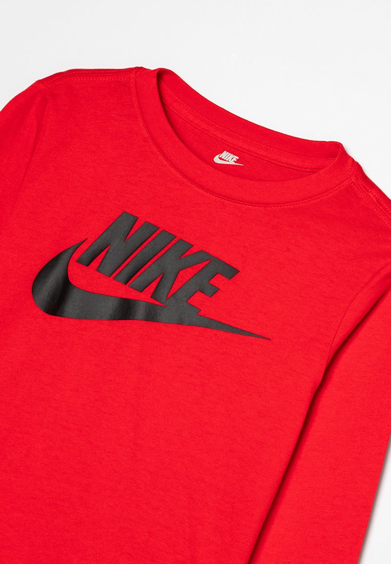 Chemise rouge à manches longues en coton. Présente un grand logo Nike noir imprimé sur la poitrine. Col rond, coupe standard.
