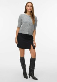 Gray knitted cardigan with short sleeves and button front, paired with a black mini skirt featuring a side slit. Black knee-high heeled boots.