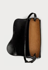 Fekete lakkbőr táska sima külsővel, nyitott, világosbarna bélésű belsővel. Ívelt formája és két rövid fogantyúja van.