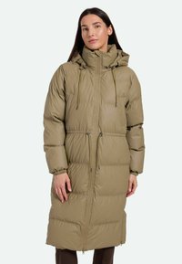 Parka larga y acolchada de color verde oliva con un alto cuello, cordones ajustables, cierre de cremallera en la parte delantera y puños elásticos. Textura suave y diseño cálido.