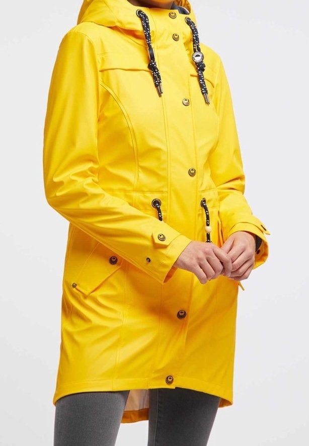 Gul vattentät parka med huva, framknappar, dragsko i midjan och två sidofickor. Har svarta repdetaljer och muddar.