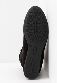 Černá semišová kotníková bota s texturovanou podrážkou, opatřená bočním zipem a hladkým, zakřiveným tvarem. Velikost uvedena jako 37.