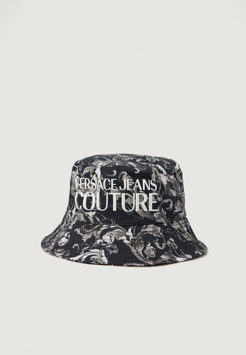 Čierny vedierkový klobúk s bielym logom "VERSACE JEANS COUTURE". Má zložitý šedý kvetinový vzor; vyrobený z textílie s hladkou textúrou.