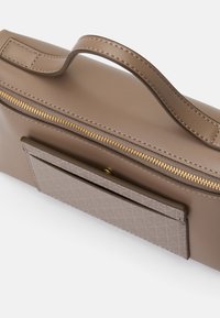 Borsa a mano in pelle marrone con zip, tasca frontale testurizzata e manico prominente. Presenta accenti in metallo dorato e una superficie liscia.