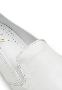 Bottine blanche en cuir texturé. Dispose d'un bout arrondi, de détails cousus et d'une doublure lisse. Logo doré embossé à l'intérieur.