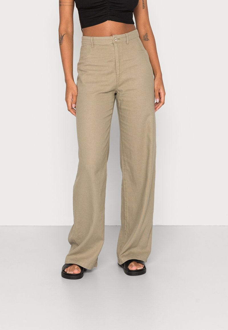Beżowe spodnie z szerokimi nogawkami, wykonane z lekkiego materiału o gładkiej fakturze i wysokim stanie. Posiadają kieszenie z przodu oraz zapięcie na guzik.