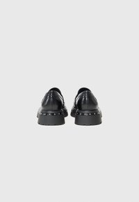 Schwarze Lederschuhe mit einer auffälligen Sohle, verziert mit Metallnieten rund um die Zwischensohle und einem runden Absatzdesign. Glatte Textur und moderne Silhouette.