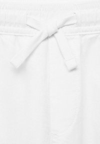 Pantalons de jogging en coton blanc avec taille à cordon de serrage et tissu doux et texturé. Comprend une poche latérale avec un simple détail de couture.