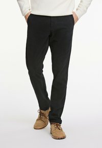 Dunkelblaue Hosen aus strukturiertem Stoff mit geradem Schnitt. Kombiniert mit tanfarbenen Wildlederschuhen mit Schnürdesign und Gummisohle.