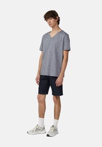 Grijze melange, T-shirt met korte mouwen en V-hals, gecombineerd met donkere denim shorts en lichte sneakers met gaasaccenten en witte sokken.