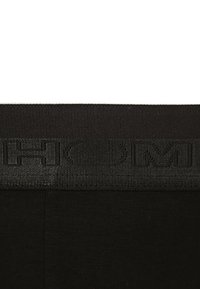 Sottoveste nera con una ampia fascia in rilievo con la scritta "HOM." Il tessuto è liscio ed elastico, progettato per il comfort.