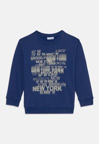 Blå genser med rund hals, med et grafisk trykk av New York- og Brooklyn-koordinater i hvit og lys grå. Myk bomullsblanding.