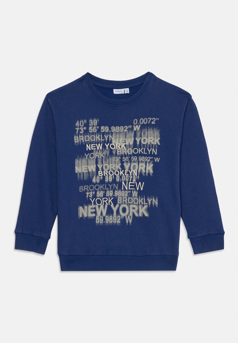 Blå genser med rund hals, med et grafisk trykk av New York- og Brooklyn-koordinater i hvit og lys grå. Myk bomullsblanding.