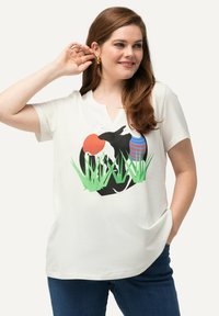 Camiseta blanca de manga corta con escote en V, que presenta un gráfico negro de un conejo, setas de colores y acentos de hierba verde. Material de algodón.