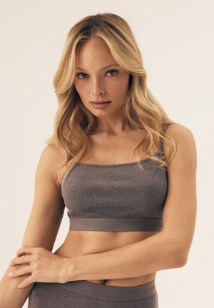 Szary, prążkowany crop top z cienkimi ramiączkami i szerokim pasem. Tekstura wydaje się miękka, z minimalnym logo na pasie.